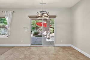 Unfurnished dining area featuring baseboards and a chandelier
