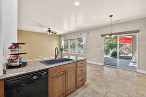 Kitchen with dishwasher, brown cabinetry, ceiling fan, hanging light fixtures, and light tile patterned floors