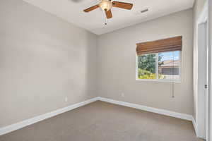 Carpeted empty room with baseboards and a ceiling fan