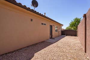 View of side of property featuring a gate, stucco siding, and a tiled roof