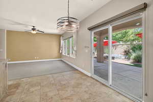 Empty room featuring a ceiling fan, a chandelier, and light carpet