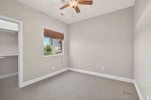Unfurnished bedroom with carpet floors, a ceiling fan, and a spacious closet
