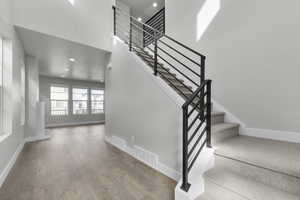 Stairway with recessed lighting, wood-type flooring, and a towering ceiling