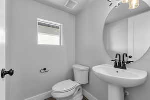 Half bath featuring toilet and baseboards
