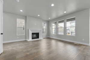 Unfurnished living room featuring a glass covered fireplace, hardwood / wood-style flooring, and recessed lighting