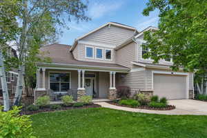 Craftsman inspired home featuring a porch, stone siding, an attached garage, and a front yard