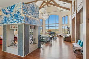 Interior space with beam ceiling, wood finished floors, a chandelier, and high vaulted ceiling