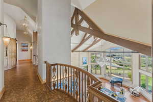 Hallway with a chandelier, high vaulted ceiling, and an upstairs landing