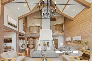 Living area with wooden walls, wood finished floors, a chandelier, and a multi sided fireplace
