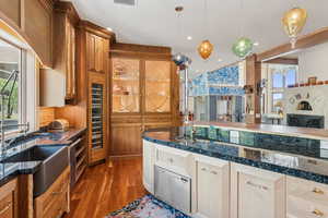 Kitchen with dark wood-style flooring, hanging light fixtures, dark stone countertops, recessed lighting, and dishwashing machine