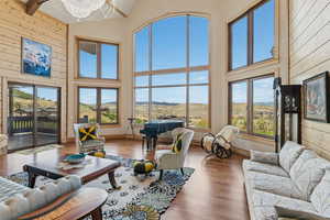 Living room featuring wood finished floors, a chandelier, wooden walls, high vaulted ceiling, and a mountain view