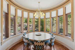 Dining room featuring healthy amount of natural light, a chandelier, and wood finished floors