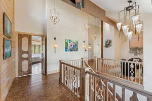 Hallway featuring a chandelier, an upstairs landing, and a towering ceiling