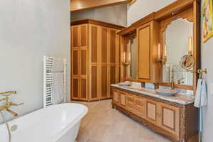 Full bath featuring a soaking tub, double vanity, and radiator