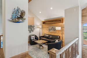 Living area with wooden walls, lofted ceiling, recessed lighting, and wood finished floors