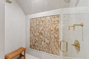 Bathroom with a tile shower, tile walls, and vaulted ceiling