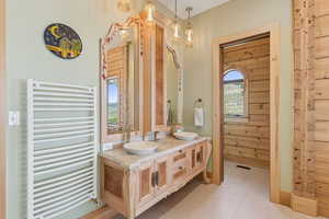 Bathroom featuring radiator heating unit, double vanity, and tile patterned floors