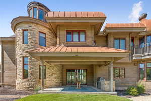 Back of property featuring a standing seam roof, exterior kitchen, stone siding, and a metal roof