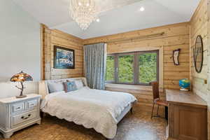 Bedroom with a chandelier, wood walls, vaulted ceiling, and tile patterned floors