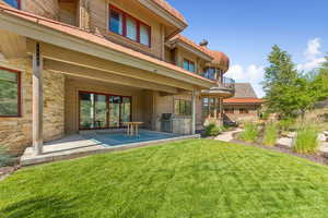 Rear view of property with stone siding, a yard, area for grilling, and a patio area