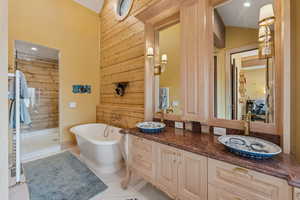 Bathroom with recessed lighting, wood walls, double vanity, a soaking tub, and tile patterned flooring
