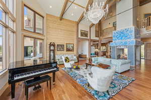 Living area with beamed ceiling, wood finished floors, a chandelier, high vaulted ceiling, and wood walls