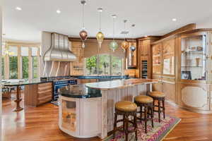 Kitchen featuring island range hood, a kitchen bar, light wood-style flooring, healthy amount of natural light, and recessed lighting
