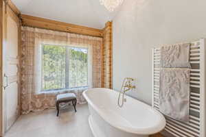 Full bathroom with a towel warmer, radiator heating unit, lofted ceiling, and a soaking tub