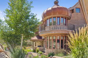 Back of property with a balcony, stone siding, and exterior kitchen