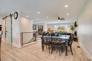 Dining room featuring a barn door, light wood-type flooring, and recessed lighting