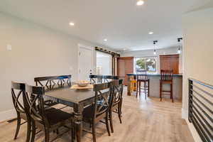 Dining area featuring light wood-type flooring, recessed lighting, and a barn door
