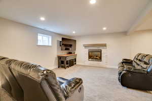 Carpeted living area with a glass covered fireplace and recessed lighting