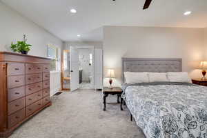 Bedroom with light colored carpet, recessed lighting, ensuite bath, and ceiling fan