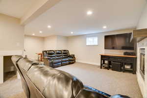 Living room with light colored carpet, recessed lighting, and a glass covered fireplace
