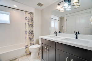 Bathroom featuring double vanity, shower / bathtub combination with curtain, recessed lighting, tile patterned flooring, and a chandelier