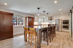 Kitchen featuring recessed lighting, appliances with stainless steel finishes, a barn door, a kitchen breakfast bar, and light wood finished floors