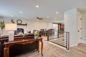 Living room featuring a textured ceiling, light wood-type flooring, recessed lighting, a wood stove, and ceiling fan