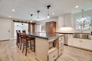 Kitchen featuring dark countertops, backsplash, a center island, light wood-style floors, and recessed lighting