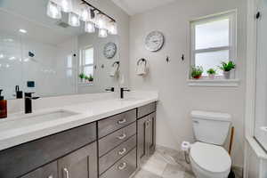 Full bath featuring double vanity and an enclosed shower