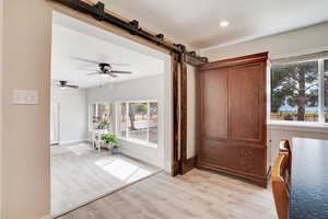 Bedroom with a barn door, light wood finished floors, and a ceiling fan