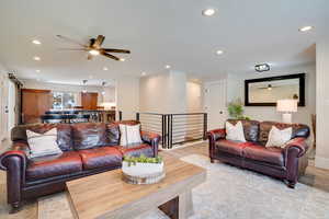 Living area with ceiling fan, light wood-style flooring, recessed lighting, and a barn door