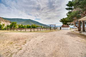 View of dirt / gravel road featuring an enclosed riding area, a mountain view, and a view of countryside