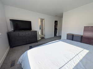Carpeted bedroom featuring a walk in closet and baseboards