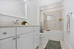 Full bath featuring vanity, shower / bath combo with shower curtain, and marble finish flooring