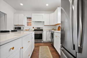 Kitchen featuring appliances with stainless steel finishes, dark wood finished floors, white cabinets, recessed lighting, and light stone countertops