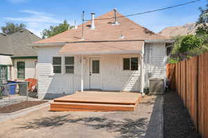 Back of property with a shingled roof and a wooden deck