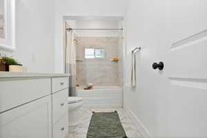 Bathroom with vanity, shower / bath combo with shower curtain, and marble finish floors