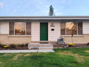 View of exterior entry featuring brick siding and a yard