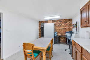 Home office with crown molding, brick wall, and light tile patterned flooring