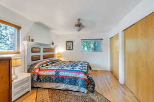 Bedroom featuring light wood-type flooring, two closets, and a ceiling fan